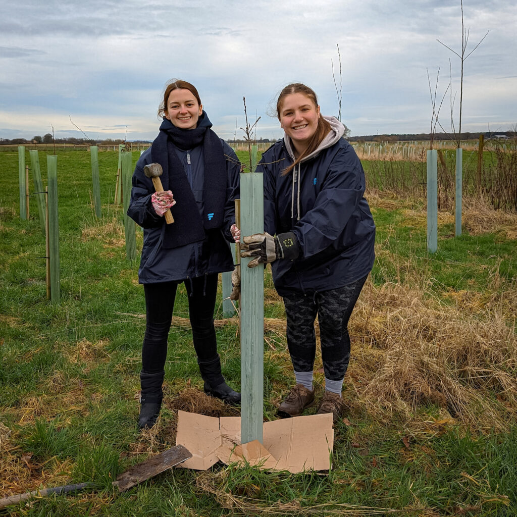 Kate and Millie proudly standing by their tree that they have made a new cardboard base for.